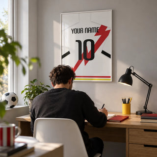 Football Shirt Poster in White with Red Lightning Bolt, framed on the wall of a compact home study for a young adult football fan (22-35) with a pale grey wall