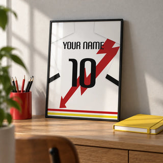 Football Shirt Poster in White with Red Lightning Bolt, a small A4 framed print leaning on an oak desk
