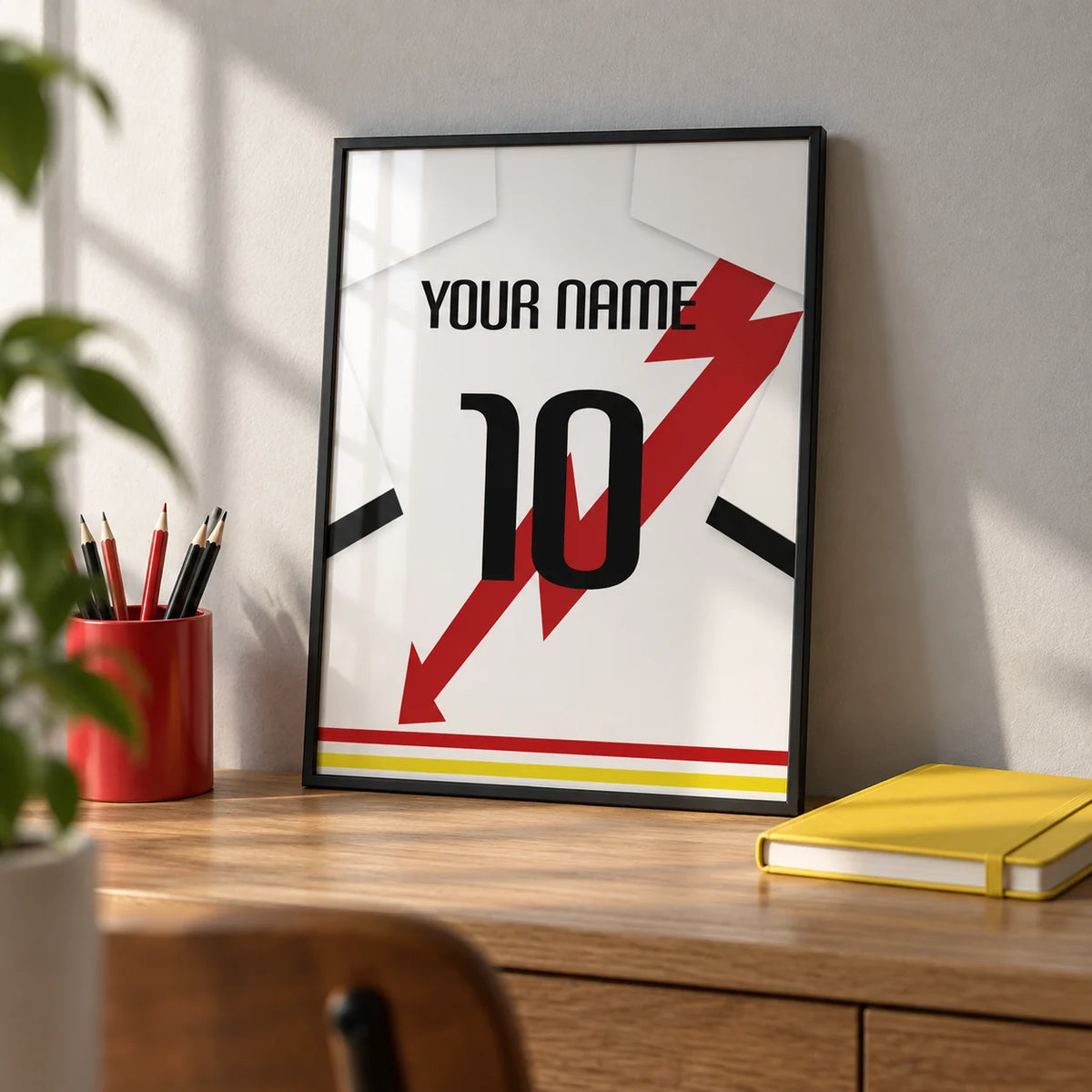 Football Shirt Poster in White with Red Lightning Bolt, a small A4 framed print leaning on an oak desk