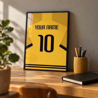 Football Shirt Poster in Yellow with Black Sleeve Stripes, a small A4 framed print leaning on an oak desk