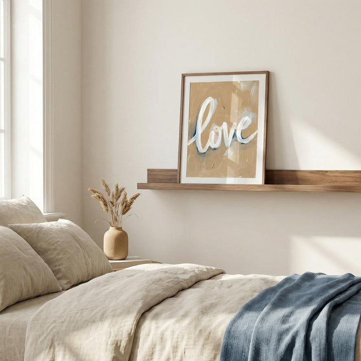 Love wall art leaning on wooden shelf with dried flowers beside bed in light bedroom