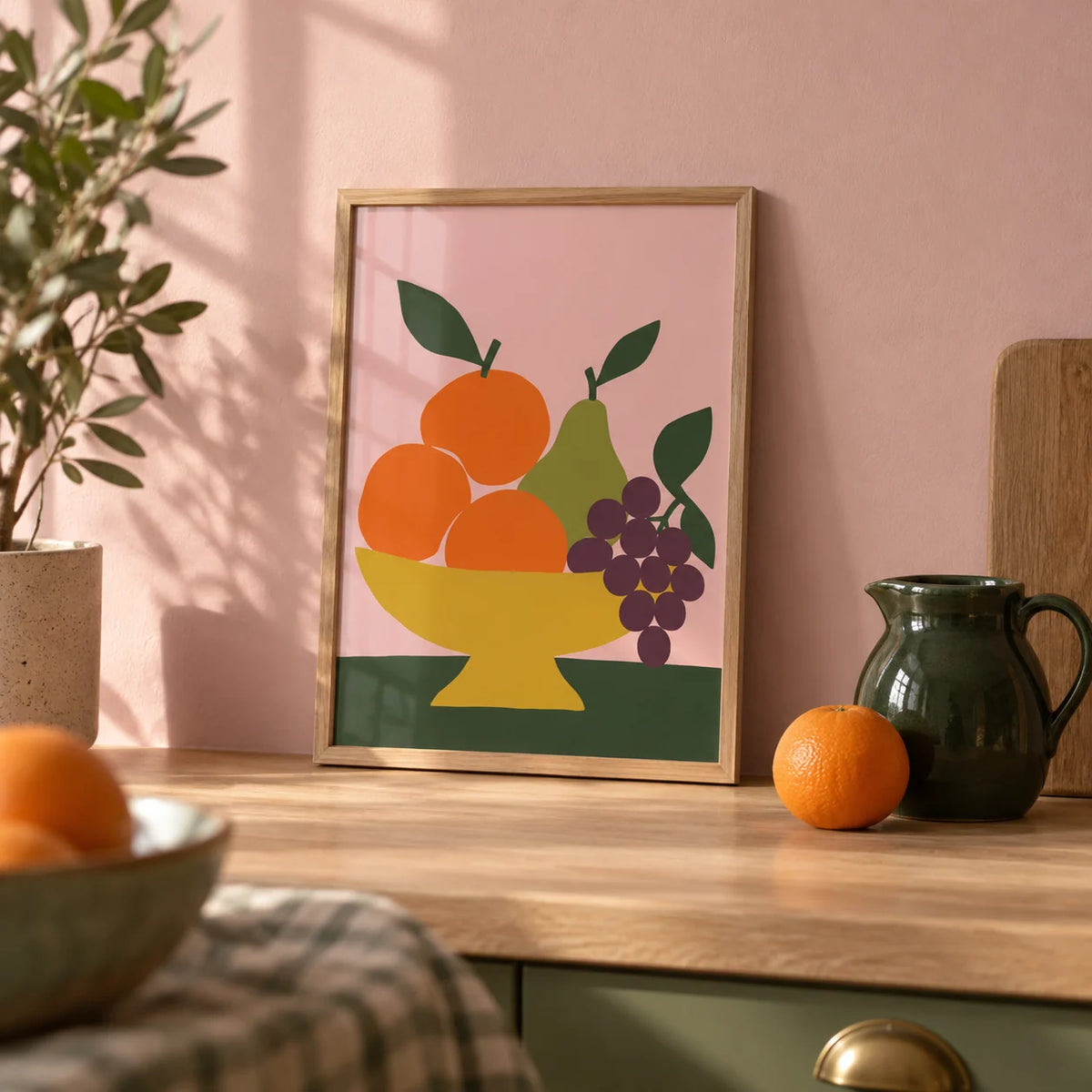 Fruit Bowl Print, a small A4 framed print leaning on a pale oak kitchen worktop