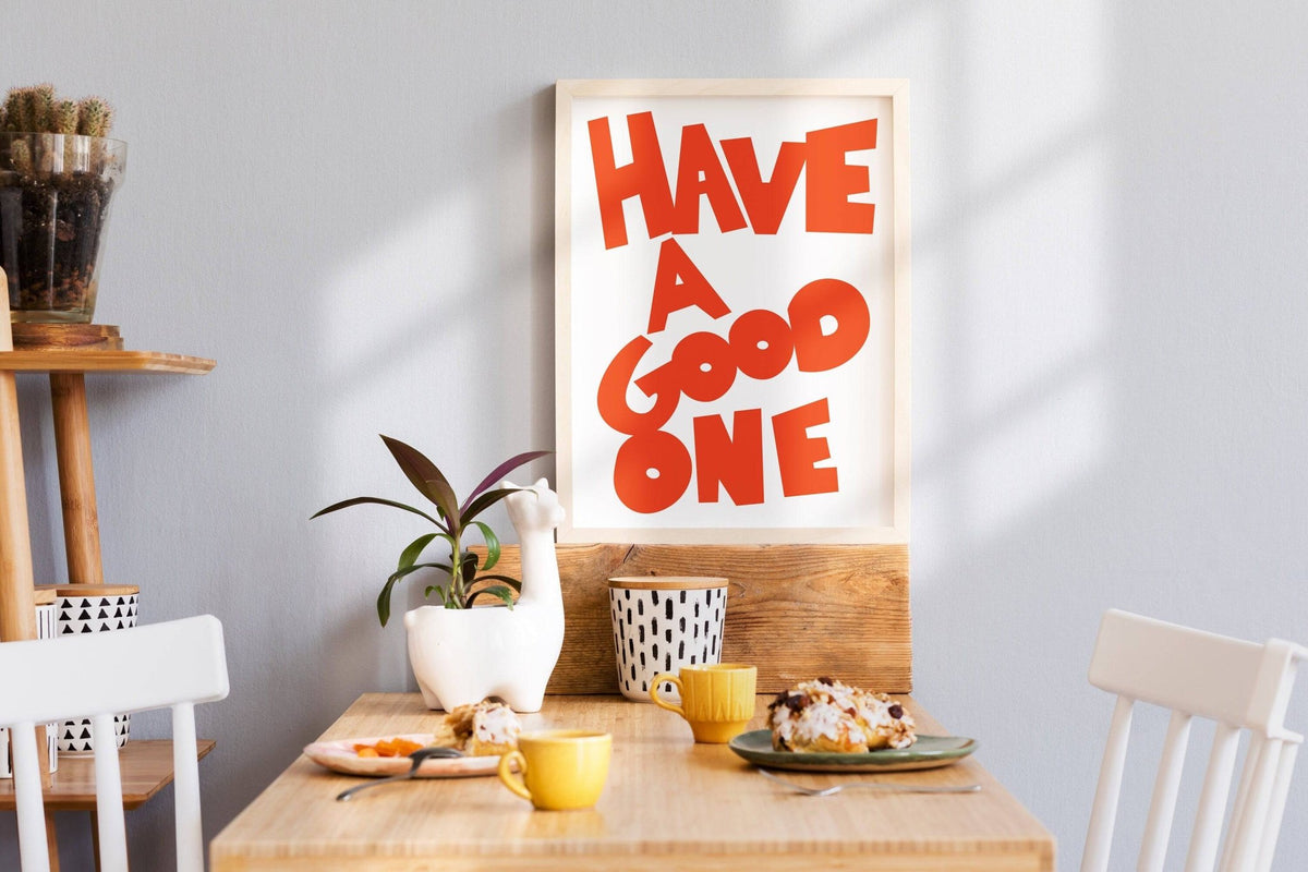 Wall Art Typography with orange text leaning on a wooden board above a kitchen table with plants and cups