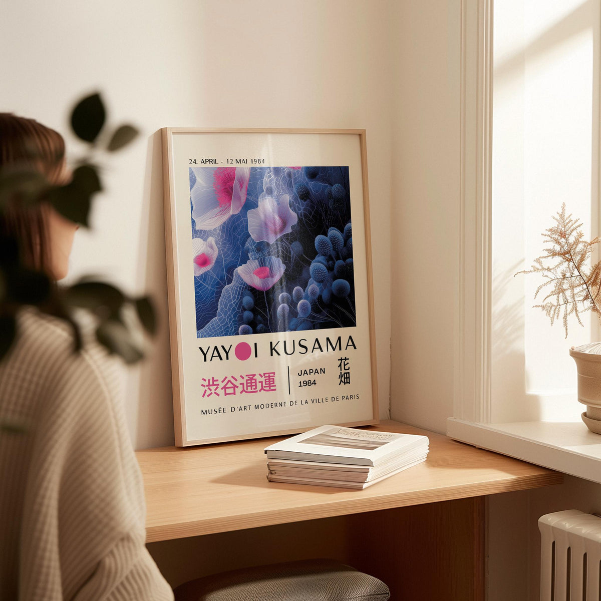 Print leaning on a shelf of purple abstract wall art with floral shapes beside a small dried plant