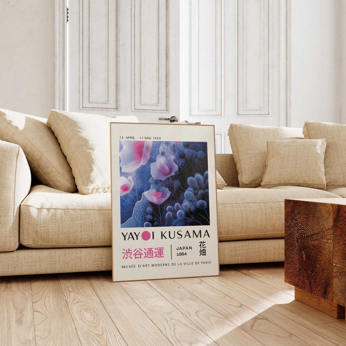 Purple abstract wall art leaning on the floor next to a beige sofa in a bright room