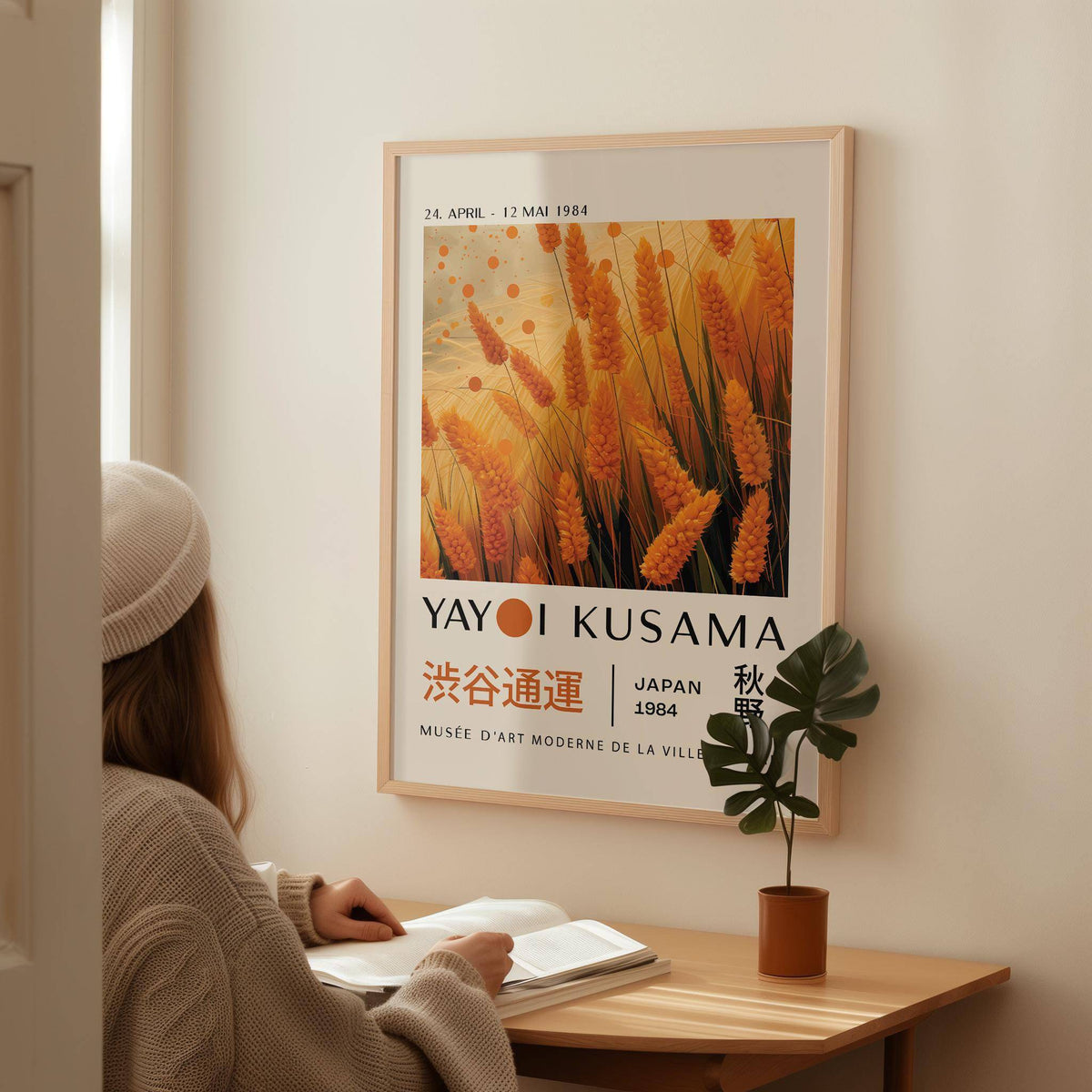 Autumnal wall art of orange wheat plants on a wall above a wooden desk with a plant