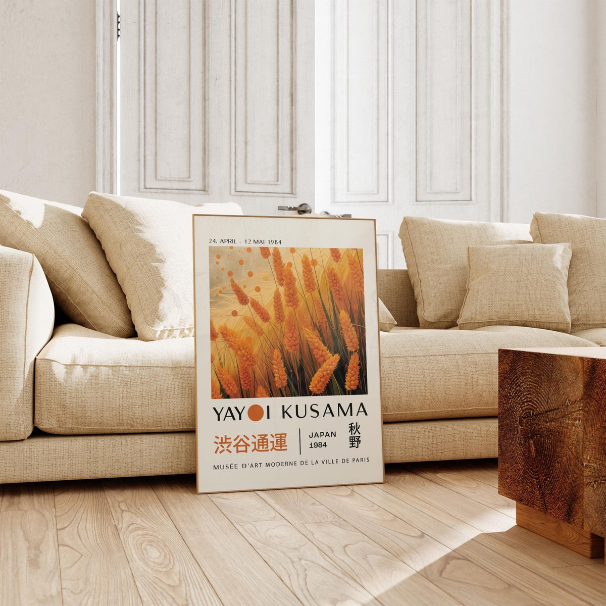 Autumnal wall art leaning on floor beside beige sofa with creamy cushions