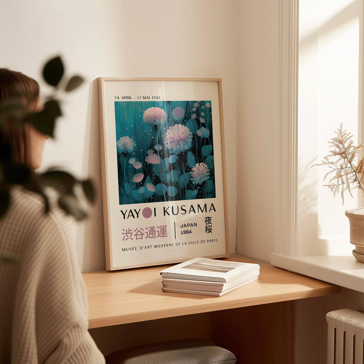 Blue and Purple Abstract Art print leaning on a shelf with pink flowers and green leaves beside a stack of books