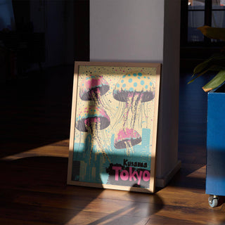 Print leaning on a floor with jellyfish and city skyline in pink blue and yellow with a blue plant pot nearby