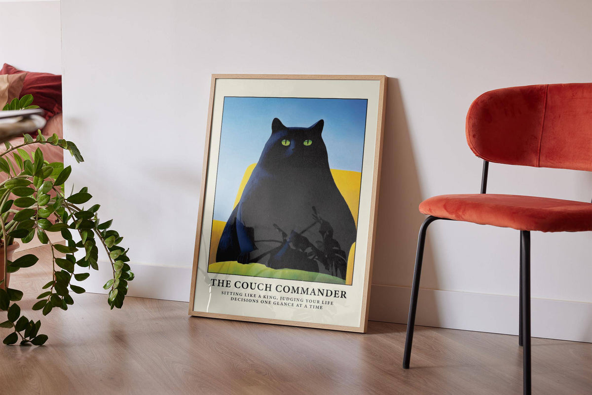 Cat Funny Poster print leaning on floor showing black cat on yellow couch beside rust velvet chair and plant