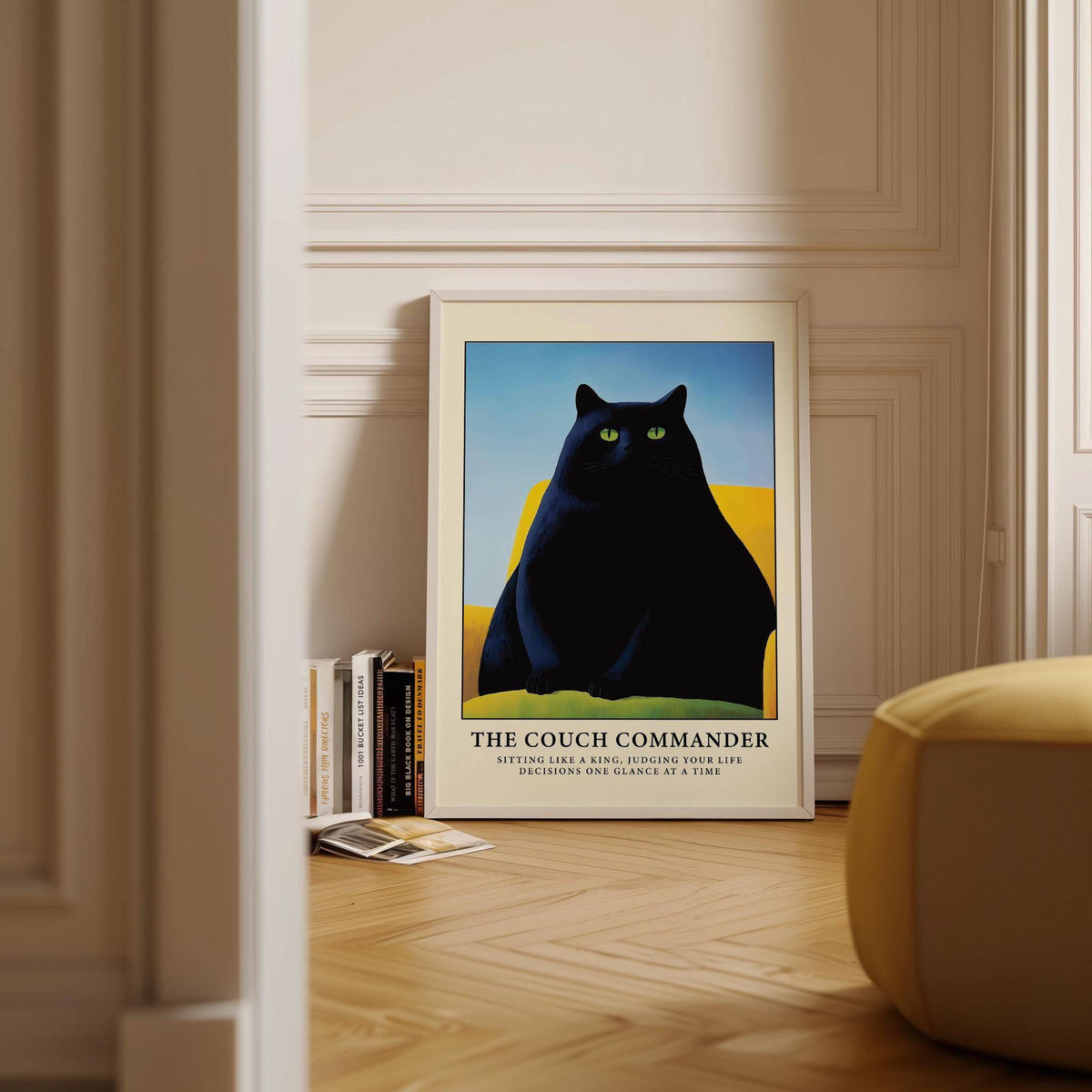 Print leaning on floor of black cat on yellow couch with blue background near books and yellow chair