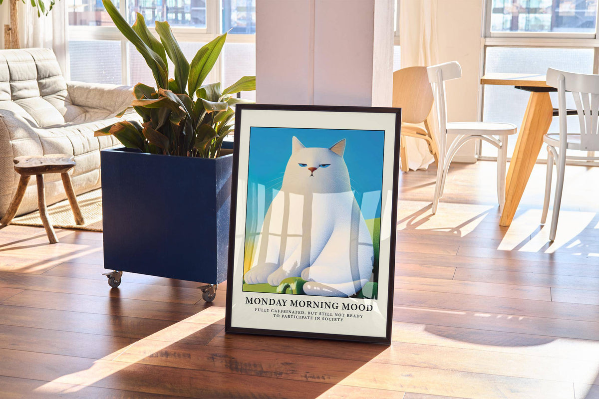 Monday Mood Cat Poster print leaning on a wooden floor with sunlight and a blue plant pot nearby