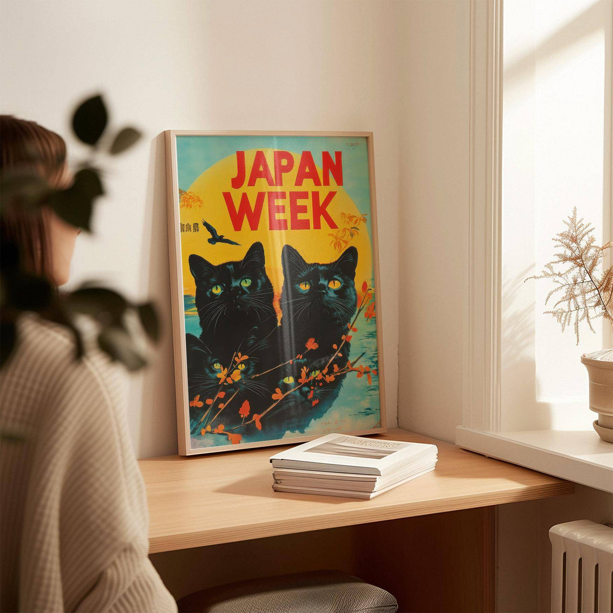 Print leaning on a desk of black cats with yellow eyes and a bold yellow sun in a warm room
