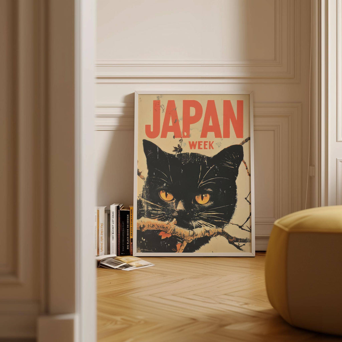 Retro Japanese Art print of black cat face with orange lettering leaning on a wooden floor near books