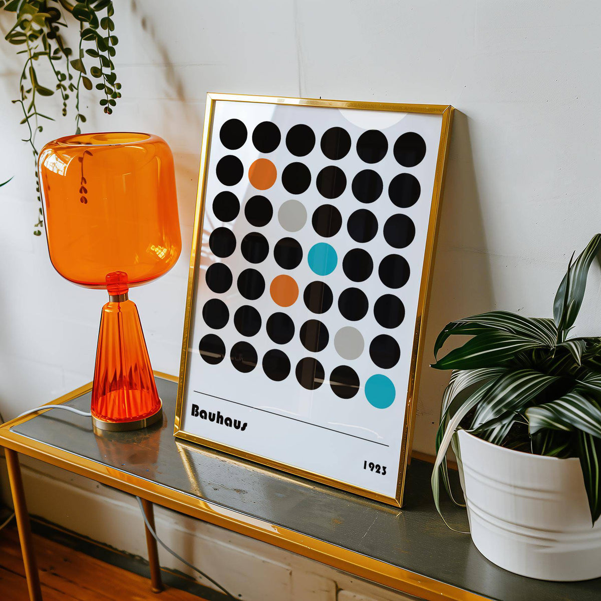 Graphic prints framed print with coloured dots leaning on a golden metal table beside plants