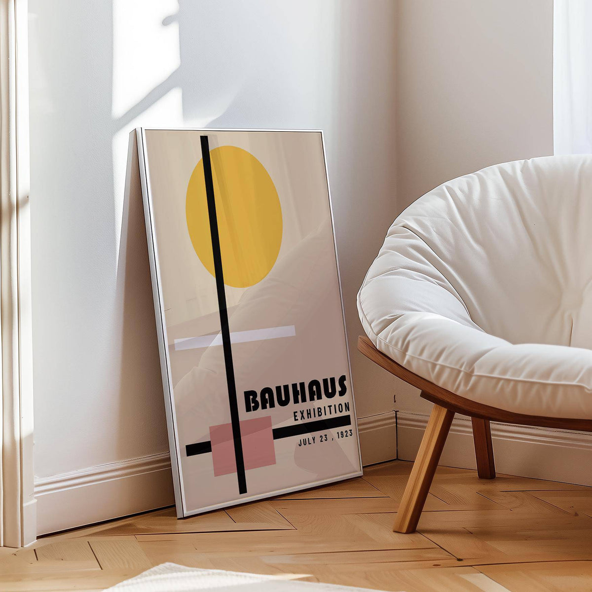 Print leaning on a floor beside a white cushioned chair with geometric shapes in muted colours