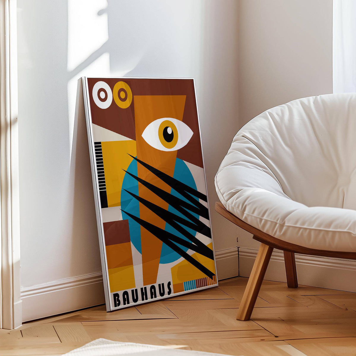 Print leaning on a floor with an abstract eye shape in brown, blue and yellow by a white chair