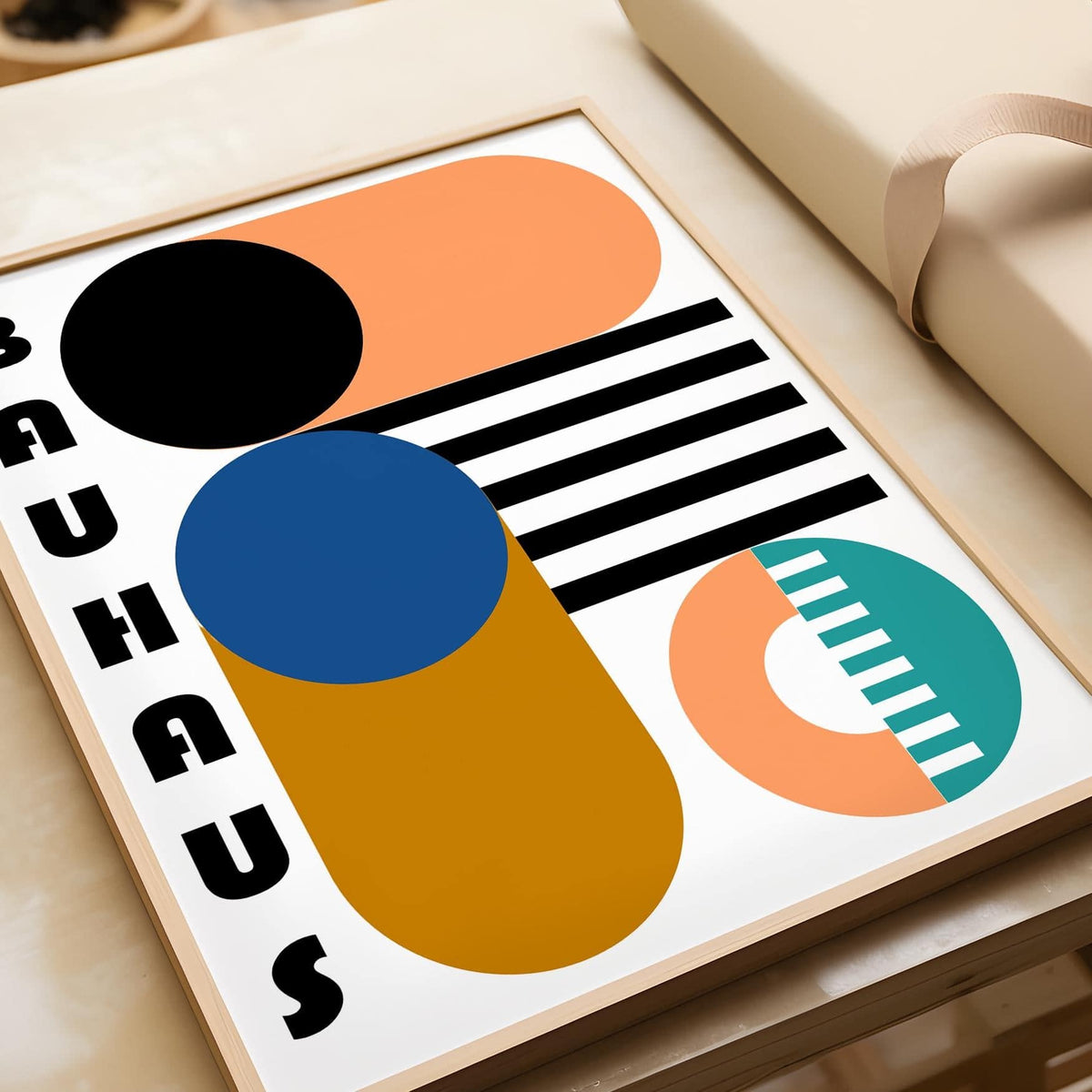 Framed close-up of Bauhaus geometric shapes print with black, blue and orange colours on a table