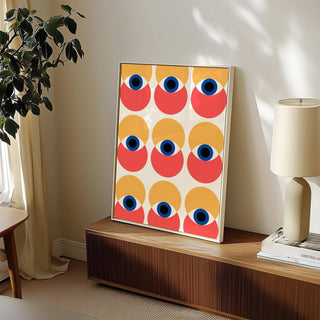 Wall Art Eye print leaning on a wood sideboard next to a lamp and a plant in a light room