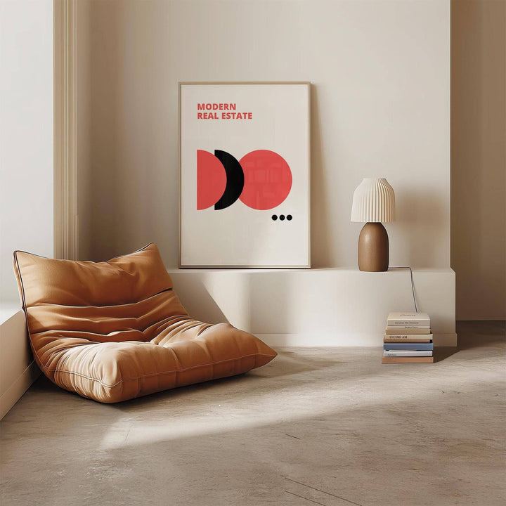 Red Black and White wall art with modern real estate text standing on a shelf beside a lamp and books
