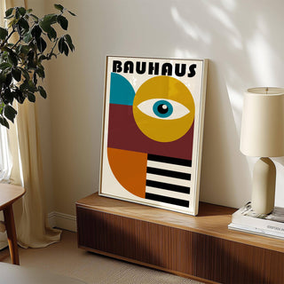 Retro wall art of a stylized eye with bold shapes in blue yellow and black leaning on a cabinet with a lamp