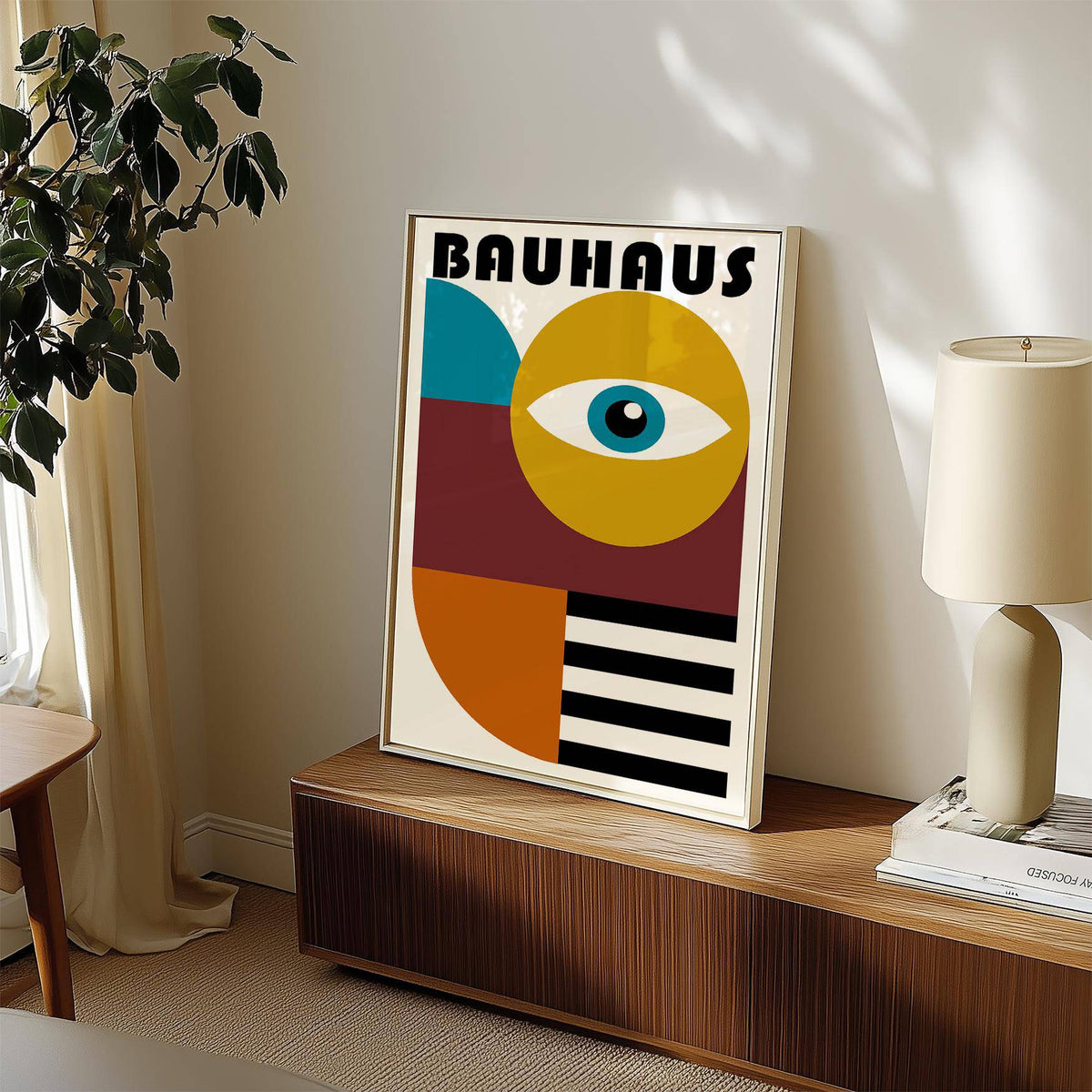 Retro wall art of a stylized eye with bold shapes in blue yellow and black leaning on a cabinet with a lamp