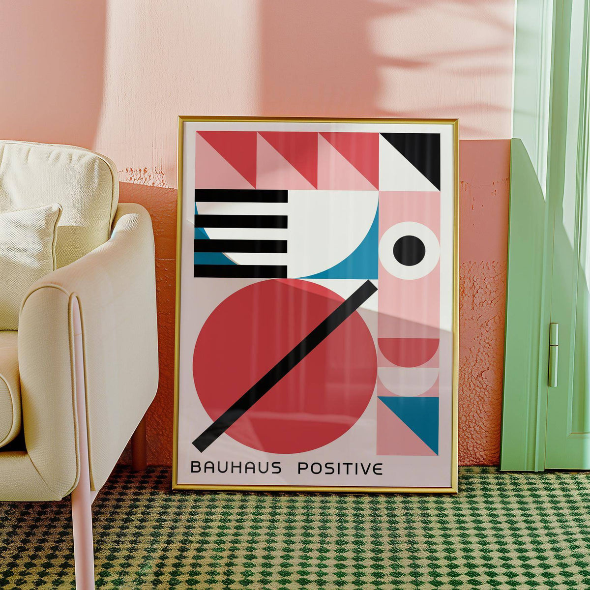 Framed print of colorful geometric art with bauhaus shapes and text leaning against a peach wall next to a cream armchair