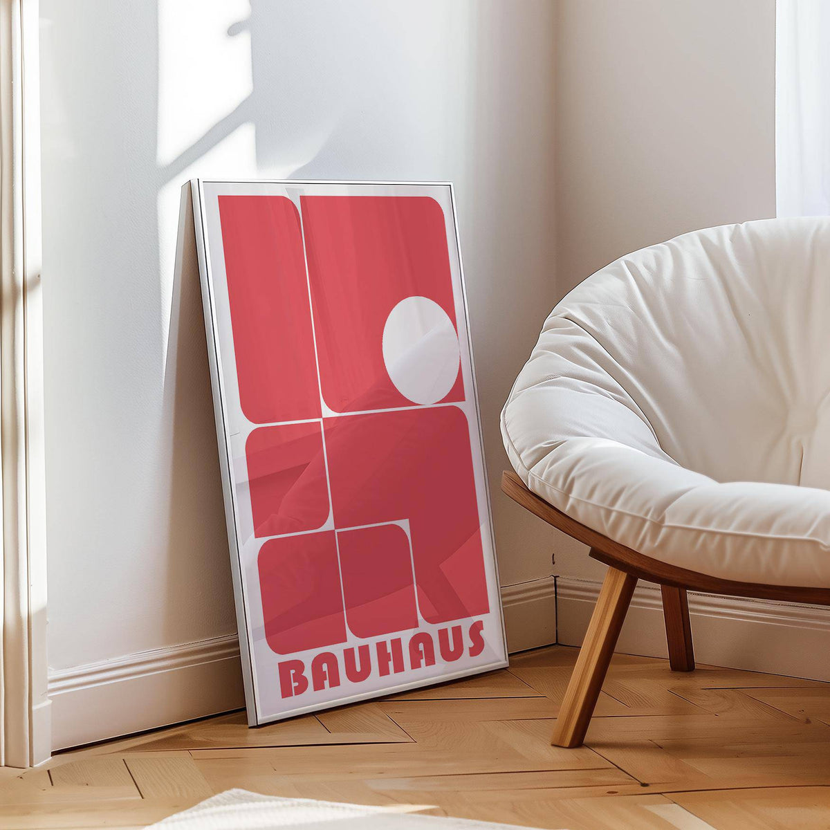 Print leaning on floor with red rounded rectangles and a white circle beside a cream cushion chair