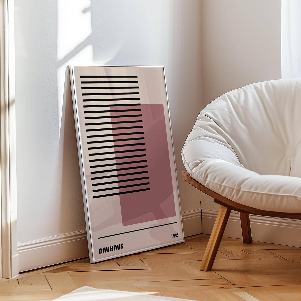Print leaning on a floor of Bauhaus 1923 Art with black lines and pink square by a white cushioned chair