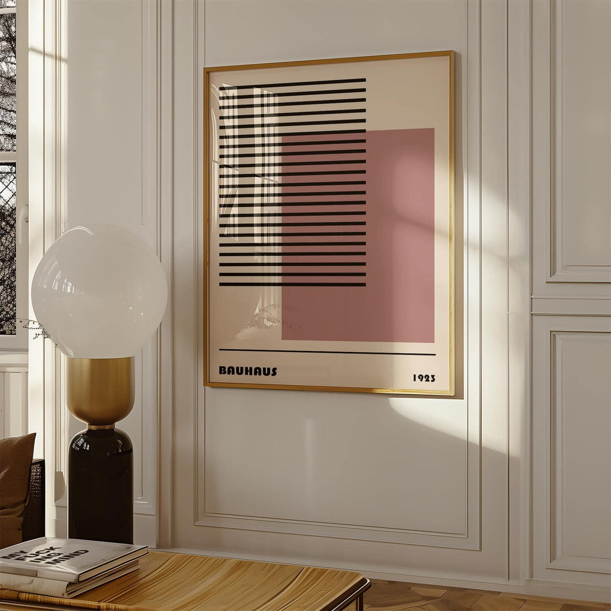 Framed Bauhaus 1923 Art print with black lines and pink square on a white wall with a lamp nearby