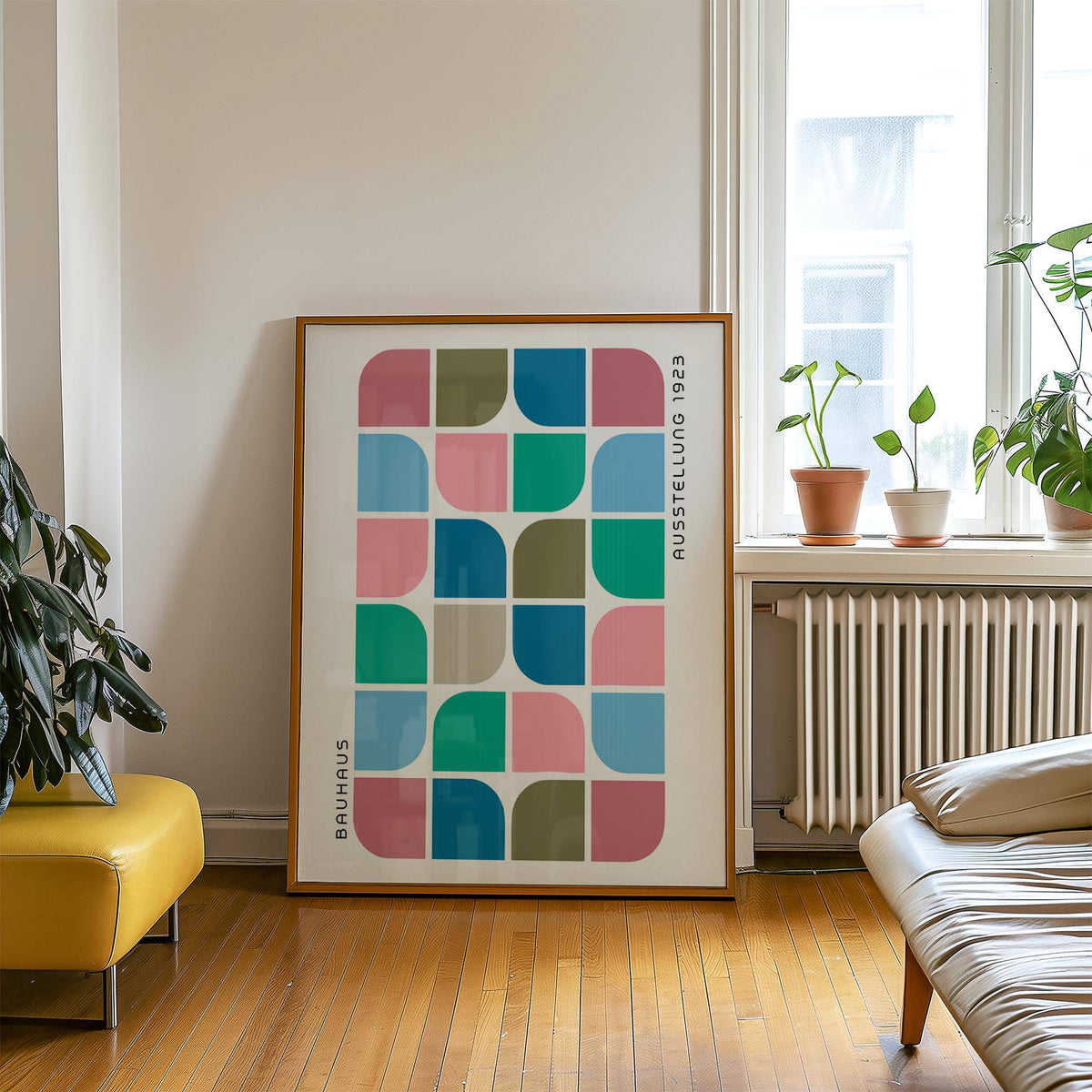 Block Colour wall art leaning on the floor with geometric blocks in blue green pink and olive near a yellow chair