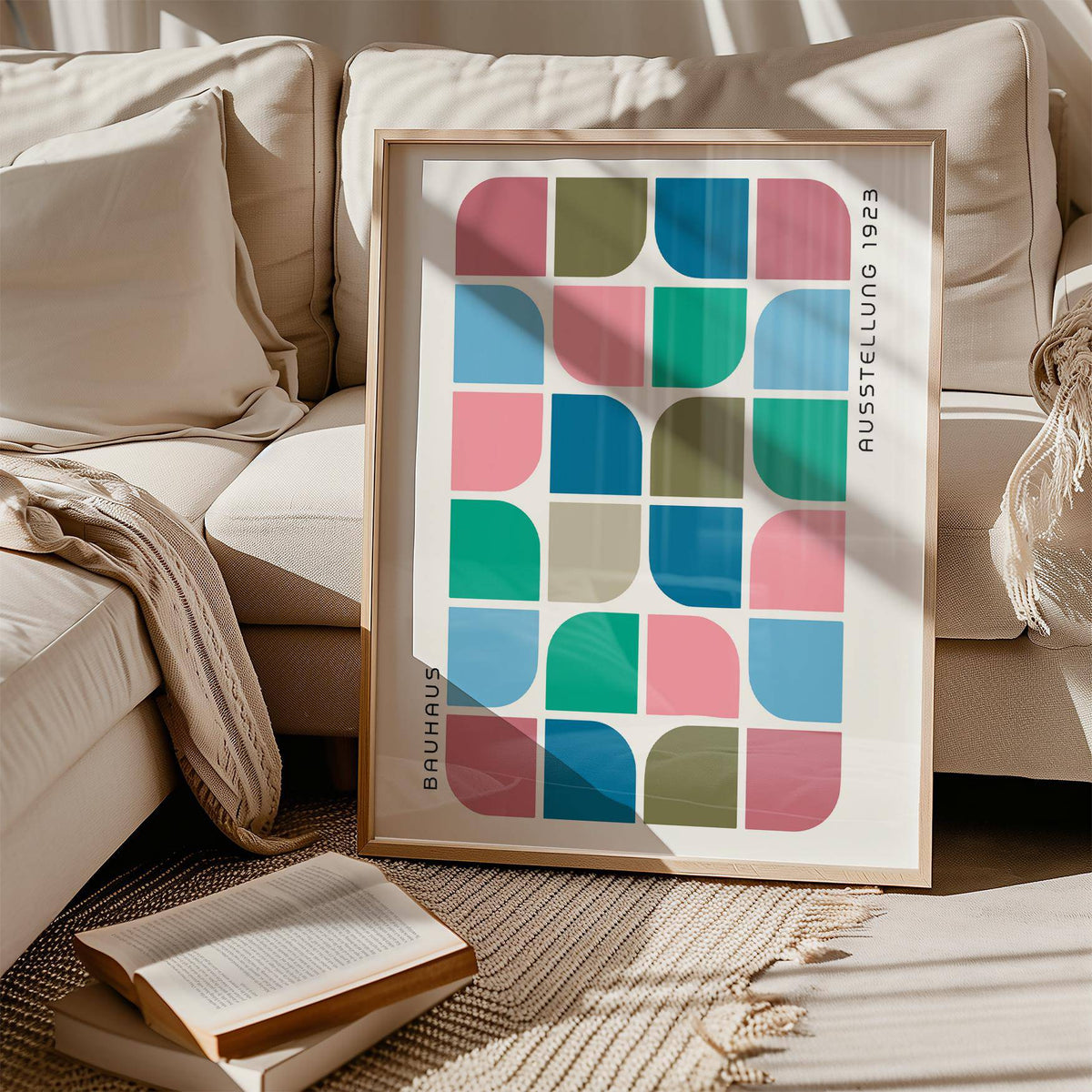 Block Colour wall art leaning on a rug beside an open book and a cream sofa in natural light