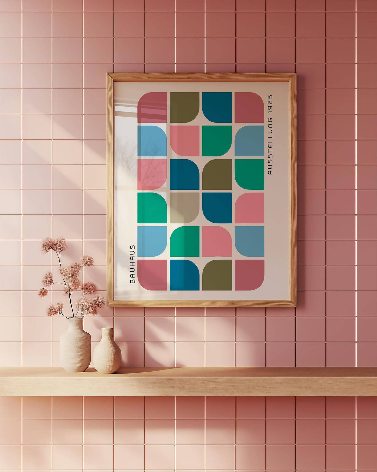 Block Colour wall art with geometric blocks in blue pink and green on a pink tiled wall above a wooden shelf with vases