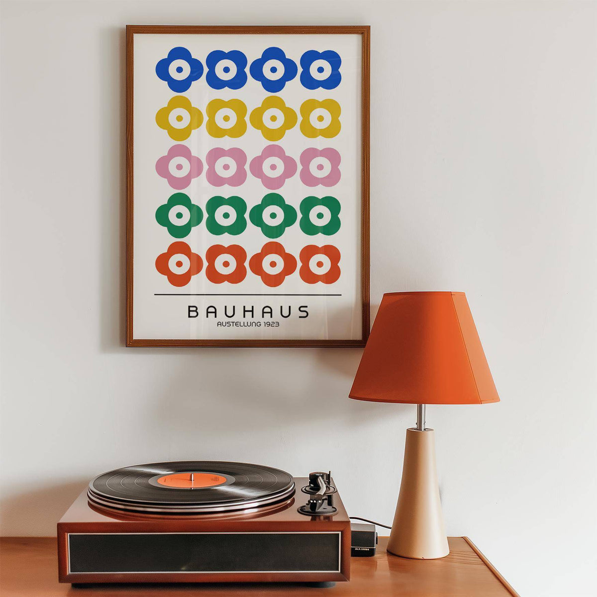 Bauhaus Print Design framed print with colourful stylised flowers above a wooden sideboard with a record player and orange lamp
