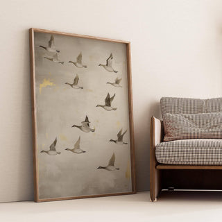 Oriental artwork of flying geese in soft browns and greys leaning on the floor by a brown sofa
