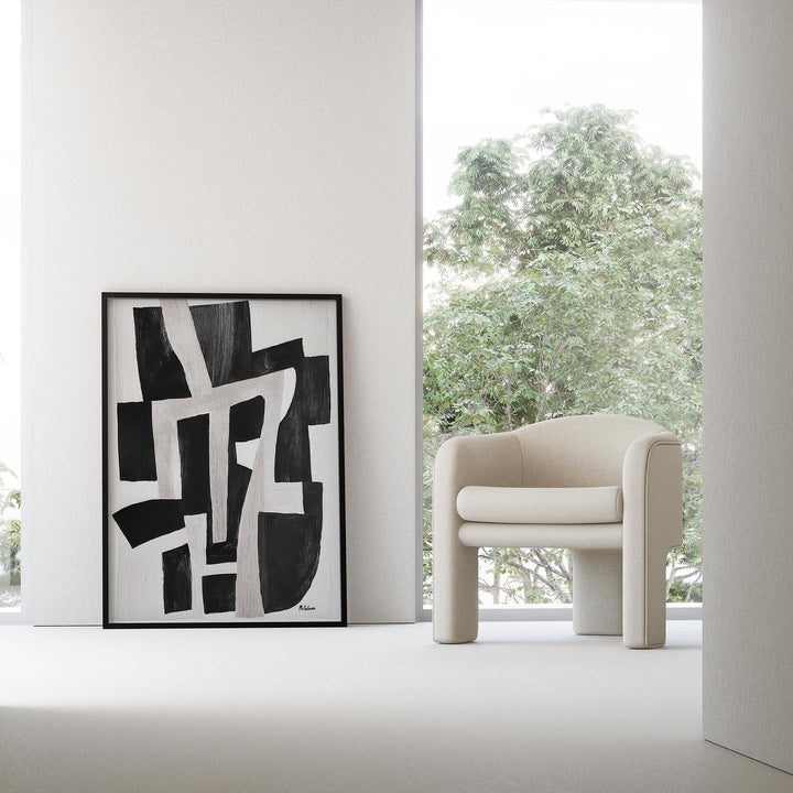 Wabi Sabi home decor print leaning on a white wall next to a cream armchair with green trees outside