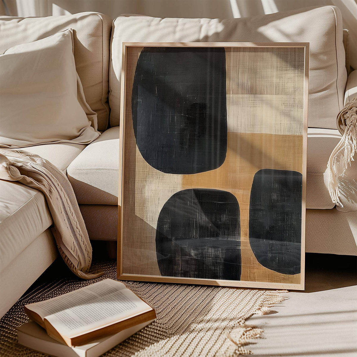 Earthy wall art with abstract black and brown shapes leaning on sofa with cushions