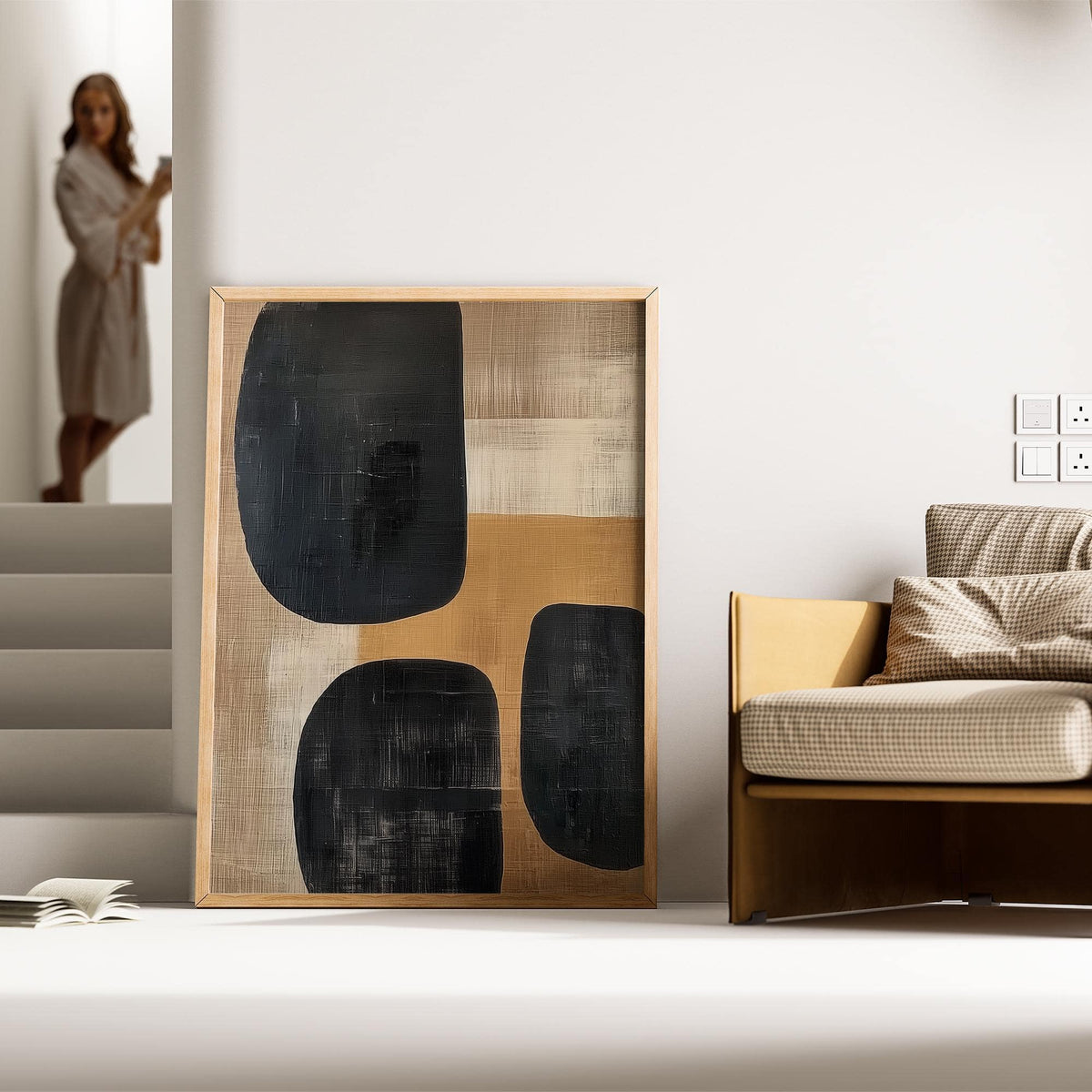 Earthy wall art leaning against a wall near a beige armchair with a cushion