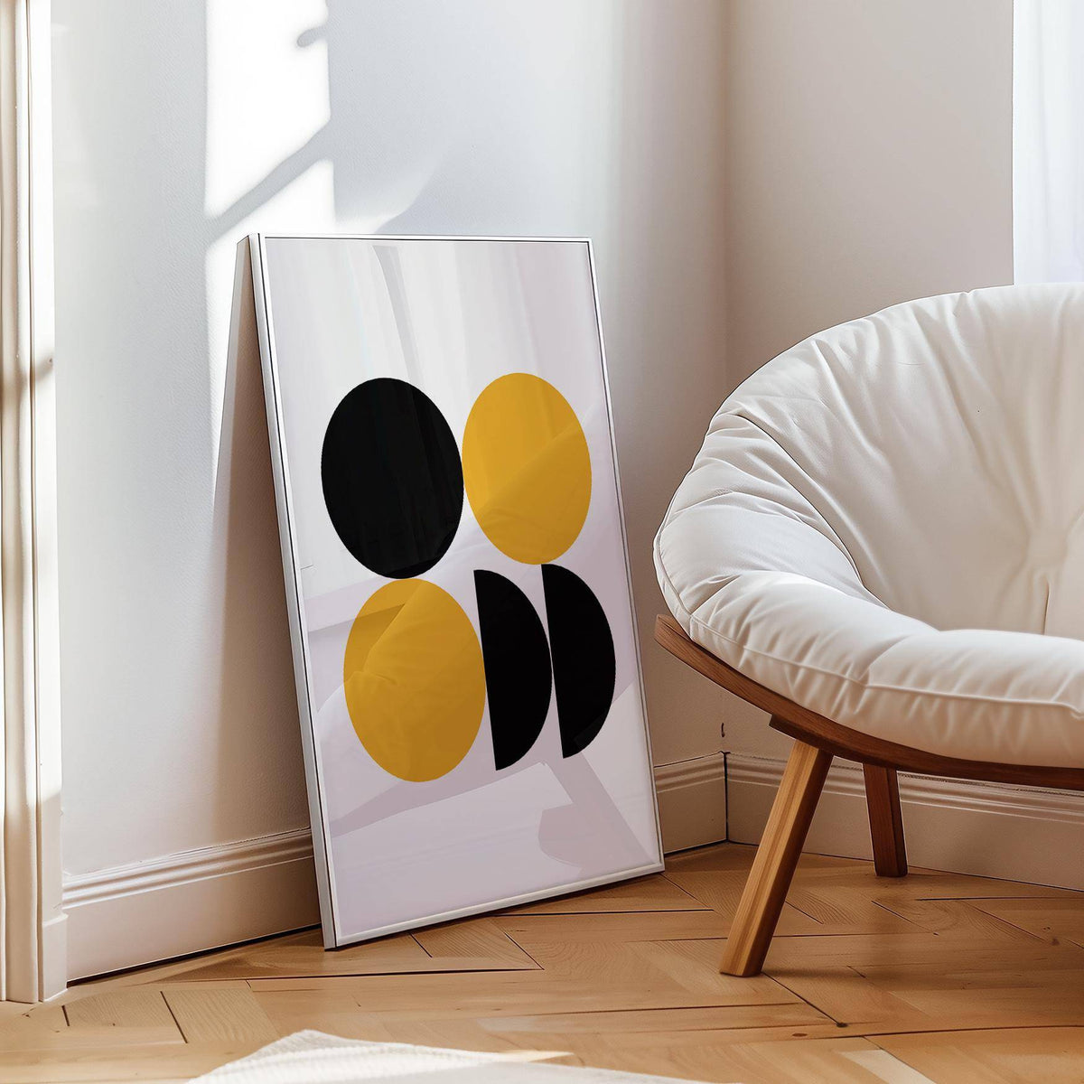Print leaning on a floor with black and yellow geometric shapes beside a white cushioned chair