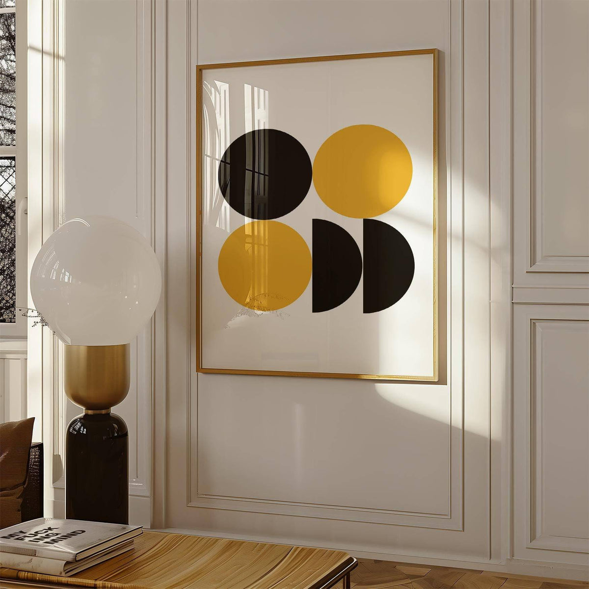 Framed geometric posters with black and yellow Bauhaus shapes on a wall with classic panelling and a lamp nearby