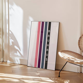 Print leaning on floor with vertical stripes in pink purple blue and black beside a woven chair