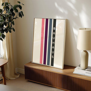 Geometric Art Wall print of vertical pink purple blue and black stripes leaning on a wooden sideboard with a lamp