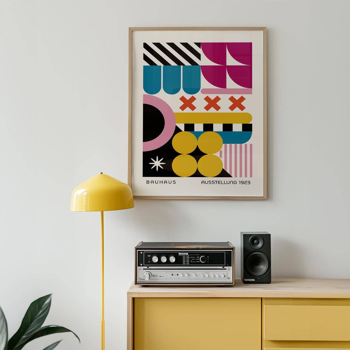 Colorful Prints framed print of geometric shapes in pink yellow and black above yellow cabinet and speaker