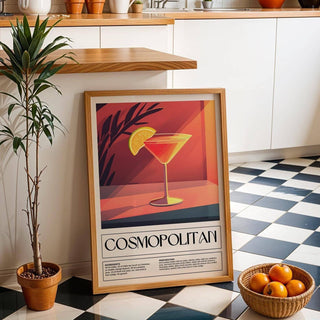 Drink Poster Art print leaning on a black and white tiled floor beside a potted plant and basket of oranges in a kitchen