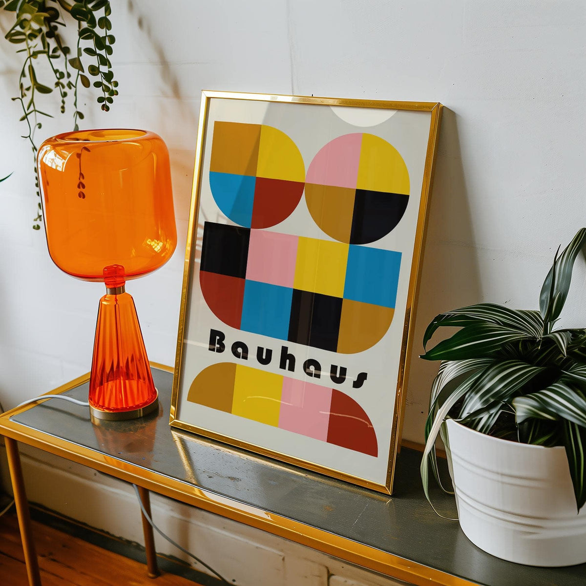 Framed print close-up of colorful geometric wall art with bauhaus style and typographic text leaning on a table with an orange lamp