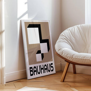 Geometric wall hanging leaning on floor next to a white cushioned wooden chair in natural light