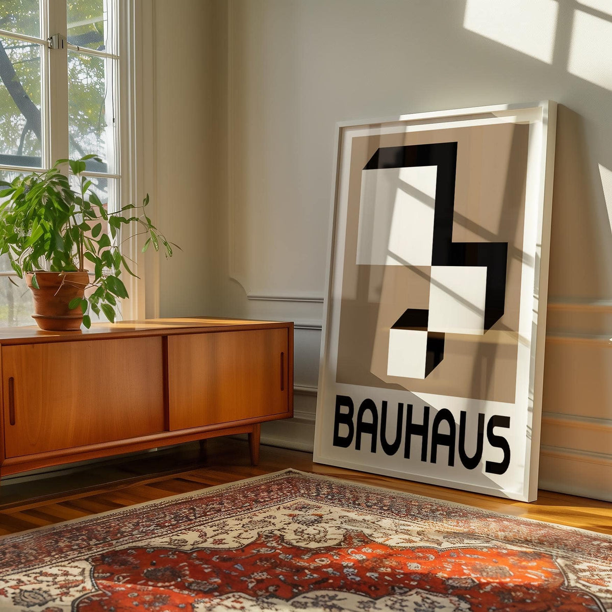 Geometric wall hanging leaning on the floor beside a wooden sideboard with a green plant in sunlight
