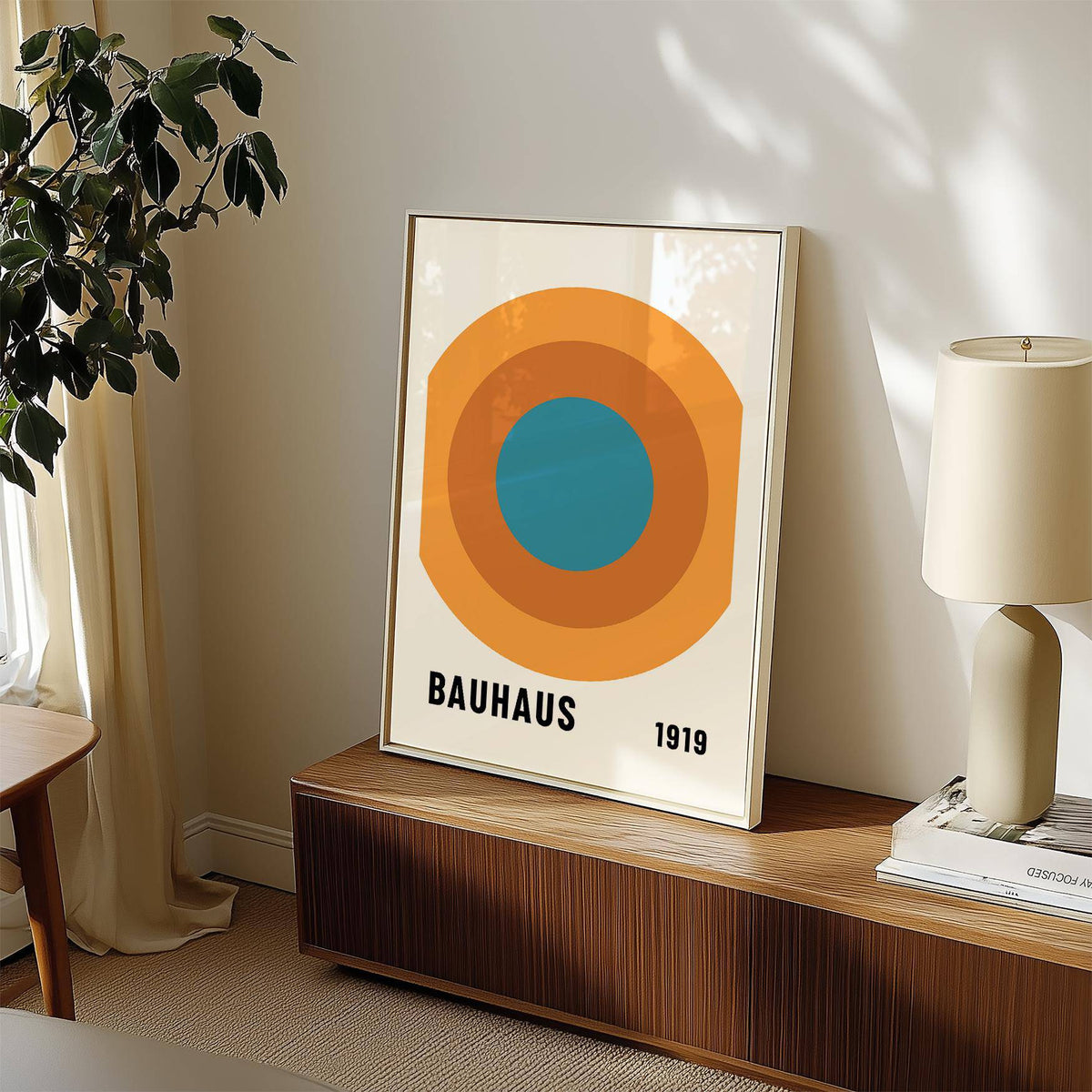 Print leaning on a sideboard of Bauhaus Circle Poster with orange and blue concentric circles and lamp nearby