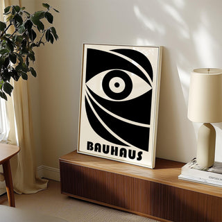 Black Eye Poster print leaning on a wooden sideboard with a plant and lamp nearby in soft natural light