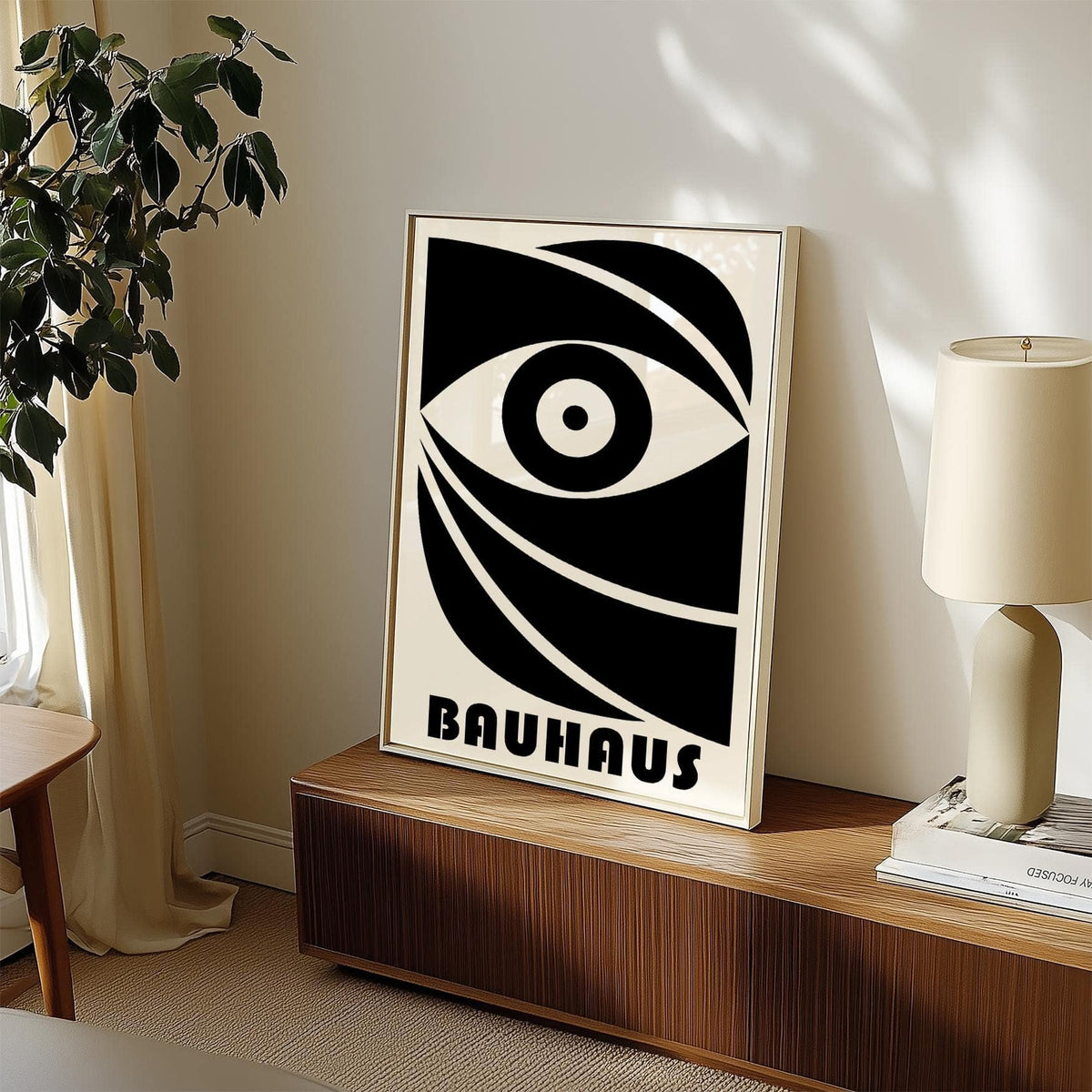 Black Eye Poster print leaning on a wooden sideboard with a plant and lamp nearby in soft natural light